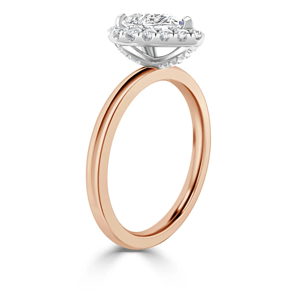 Rose gold ring with a round diamond halo setting and a white gold prong mount, shown from the side.