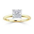 A gold band ring with a square-cut diamond in a four-prong setting, shown on a white background.