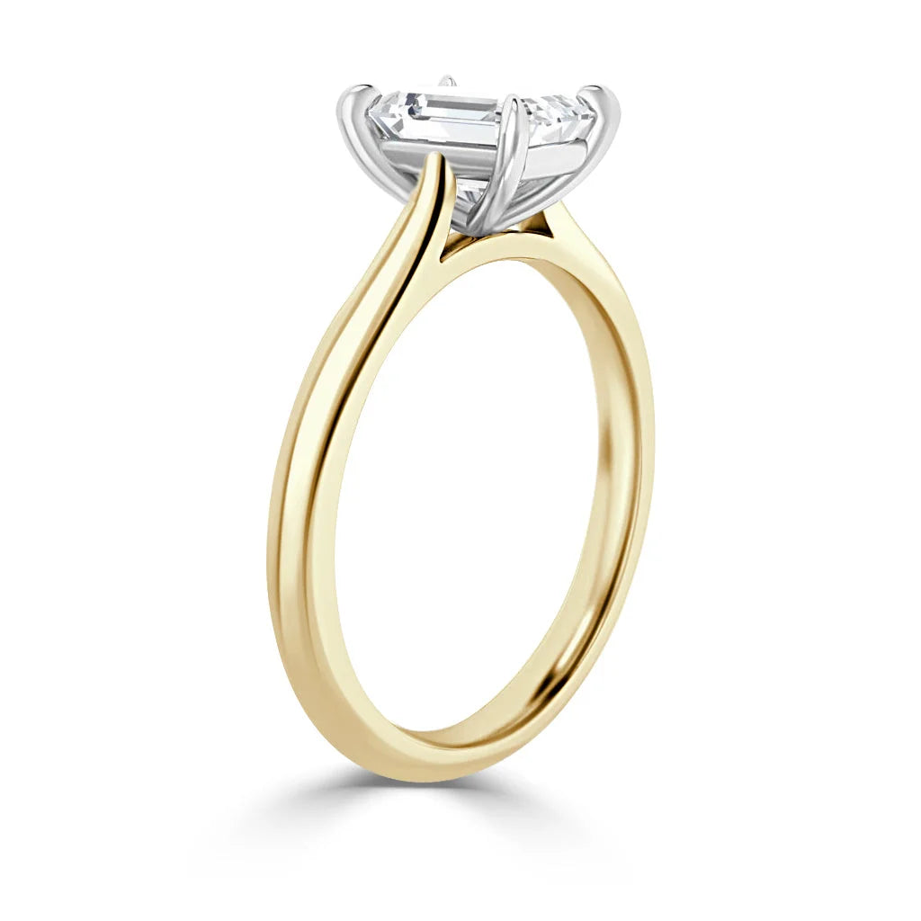 Side view of a gold ring with a large, emerald-cut diamond set in a white gold four-prong setting.