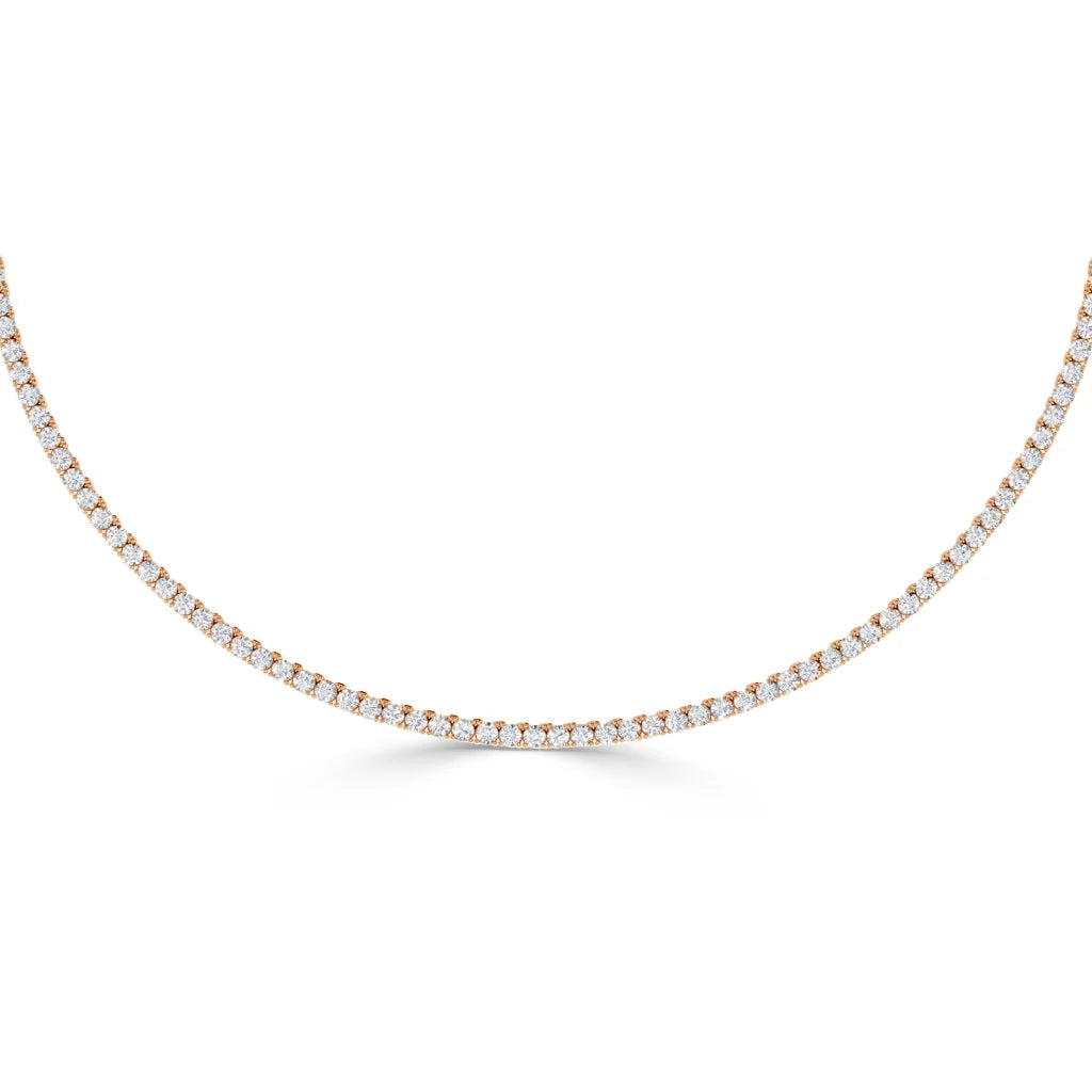 A delicate gold tennis necklace with small round white diamonds evenly set along the chain.