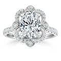 An ornate diamond ring with a large oval center stone, floral halo, and pavé diamond band.