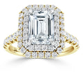 Gold ring with a large emerald-cut diamond, double halo, and pavé diamonds on band, set against white background.
