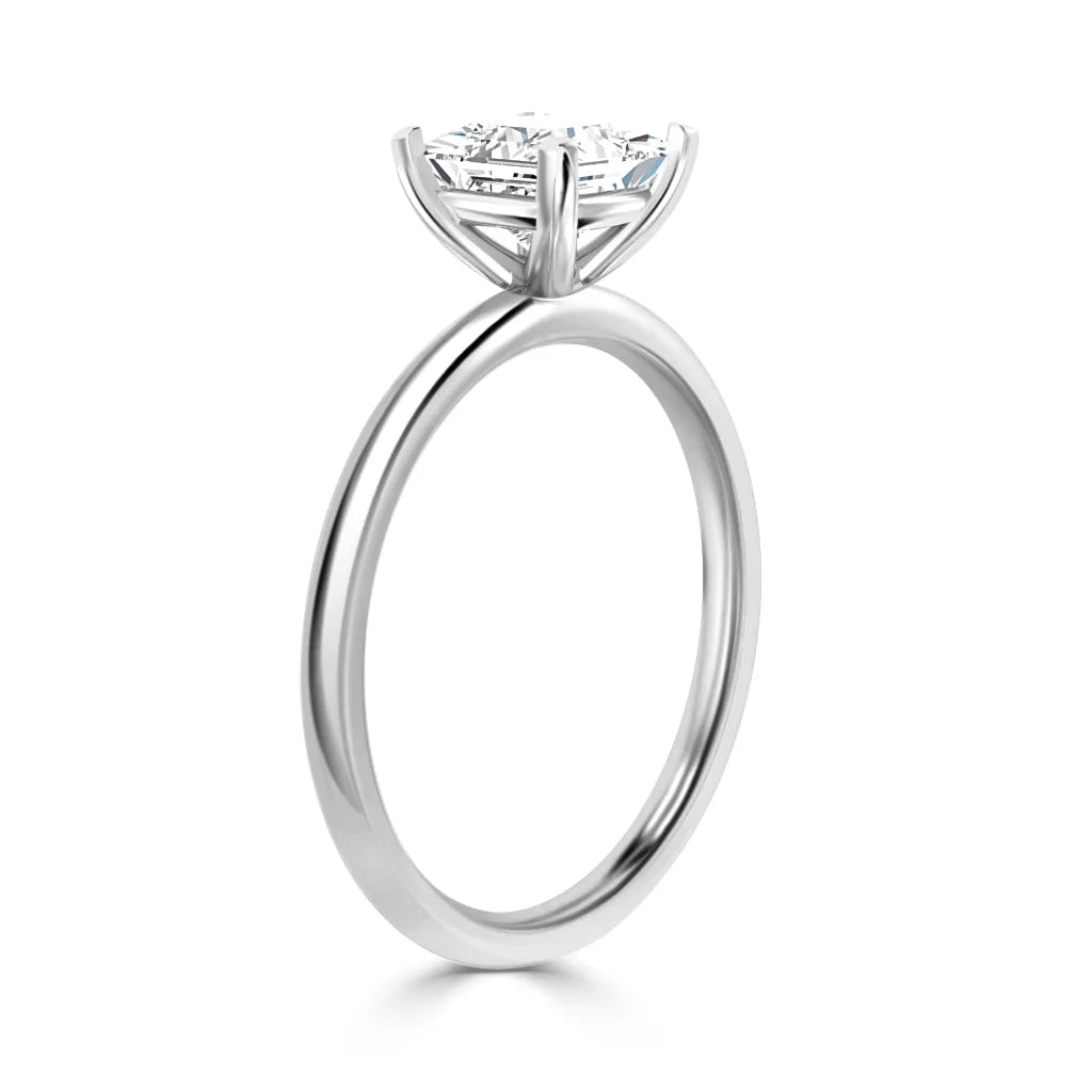 A silver solitaire ring with a round, prong-set diamond shown from a side profile on a white background.