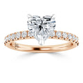 A rose gold ring with a heart-shaped diamond center and small diamonds along the band.
