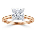 A princess-cut diamond solitaire ring with a rose gold band and four prongs securing the stone.