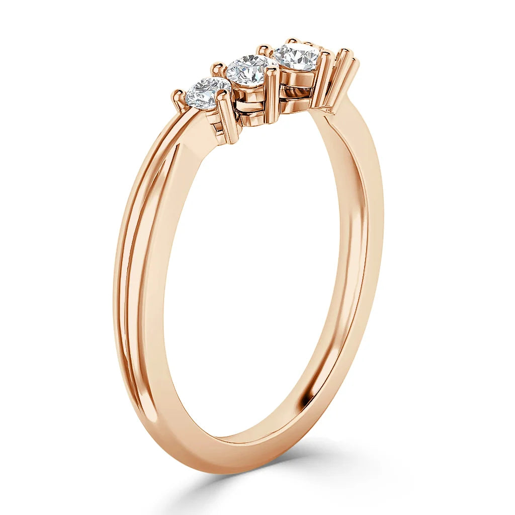 A rose gold ring with three round, white diamonds set in a row on the band, viewed at an angle.