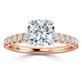 Rose gold ring with a cushion-cut diamond center and pavé diamonds along the band, shown on a white background.