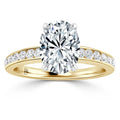 Gold ring with an oval diamond center stone and smaller diamonds set along the band, on white background.