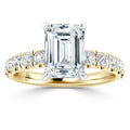 Gold ring with an emerald-cut diamond center and round diamonds set along the band.