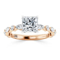 A rose gold ring with a large princess-cut diamond and side marquise diamonds set along the braided band.