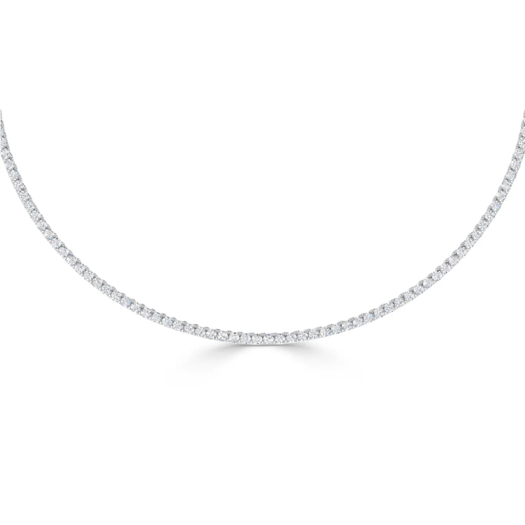 A delicate diamond tennis necklace with small round diamonds set closely in a thin, curved line on a white background.