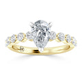 Gold ring with a pear-shaped diamond center and round diamonds set along the band, viewed from the front.