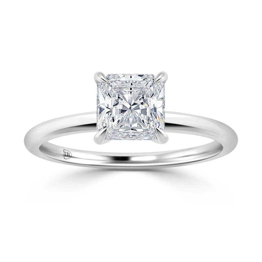 A square-cut diamond solitaire ring set on a simple, polished white gold band against a white background.