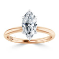 A marquise-cut diamond solitaire ring set on a simple rose gold band against a white background.