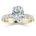 Oval-cut diamond ring with gold band and round side diamonds in a prong setting, viewed from the front.