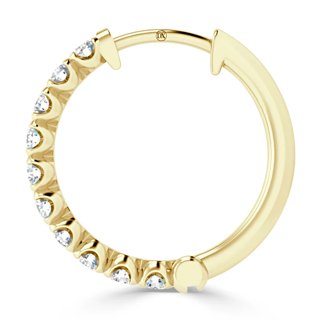 A gold hoop earring set with small round clear gemstones along half its outer edge.