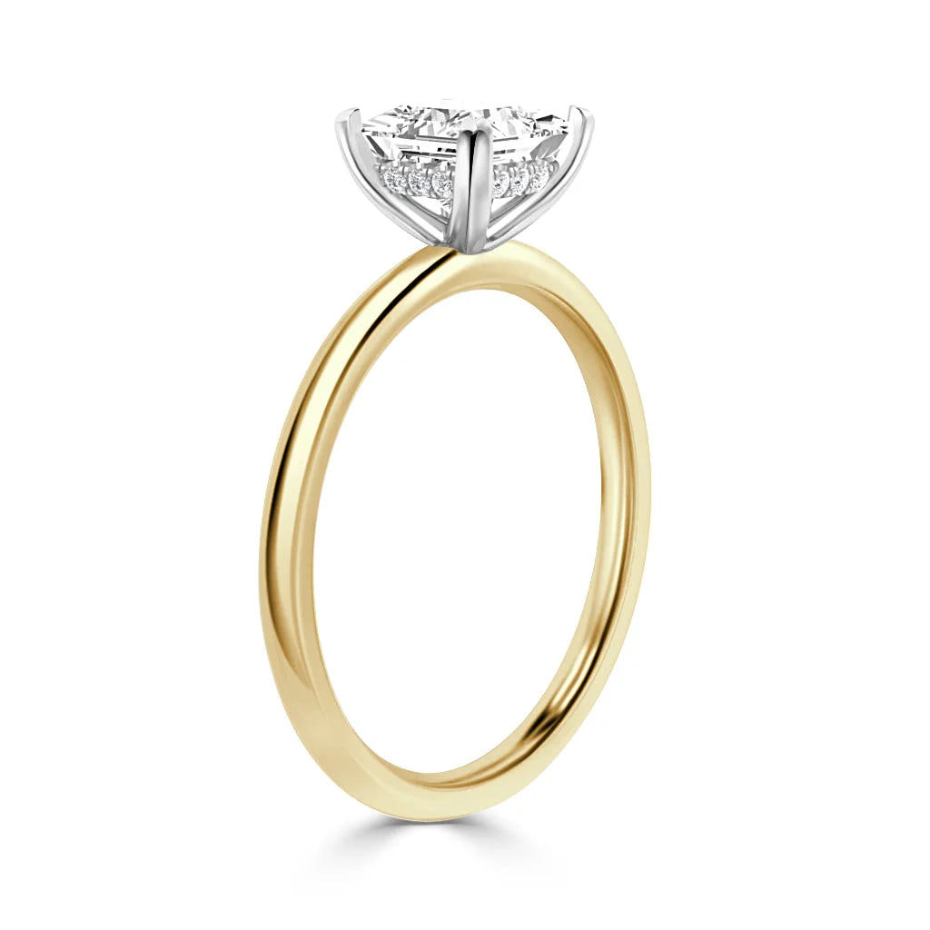 A gold ring with a round, prong-set diamond solitaire in a white gold setting on a plain band.
