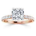 A cushion-cut diamond ring with a rose gold band featuring smaller diamonds along the band.