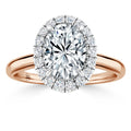 Rose gold ring with an oval-cut diamond center and a halo of smaller round diamonds on a plain band.