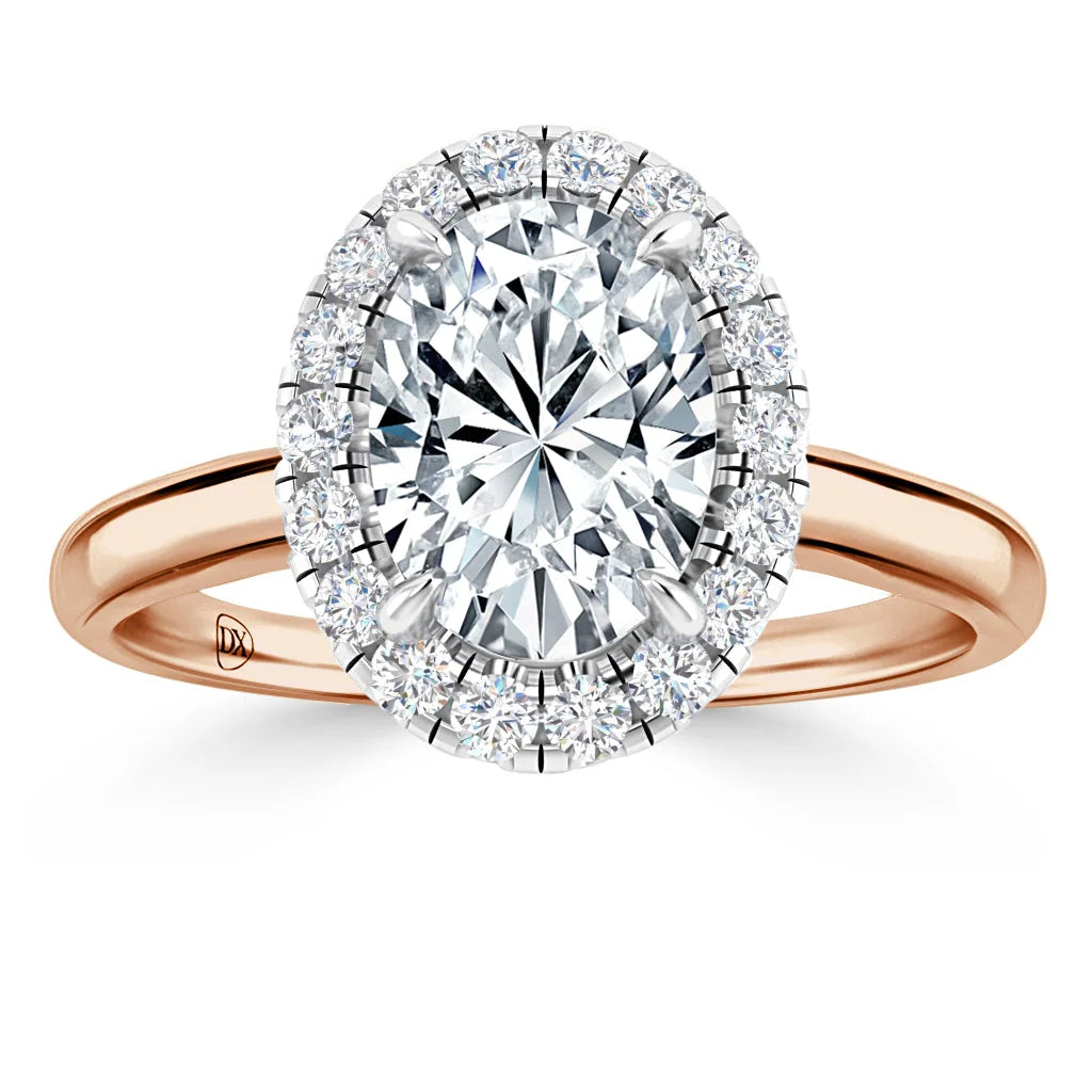 Rose gold ring with an oval-cut diamond center and a halo of smaller round diamonds on a plain band.