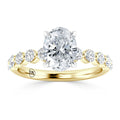 Gold ring with an oval diamond center stone, flanked by smaller round diamonds along the band.