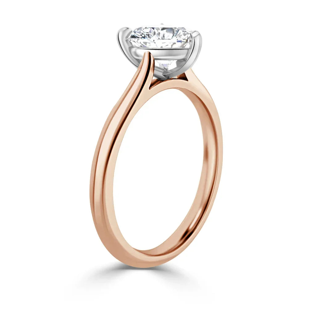 Rose gold solitaire ring with a round diamond in a white gold prong setting, shown from a side angle.