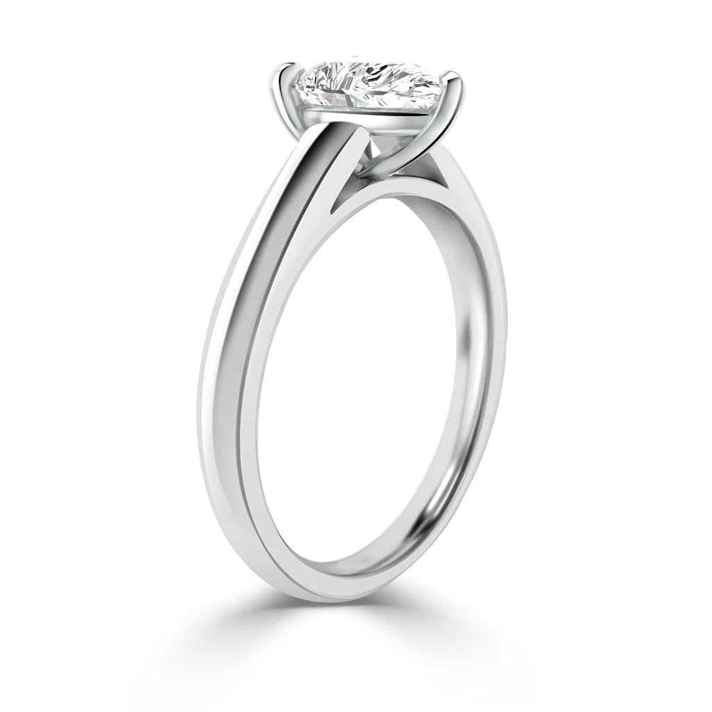 A white gold solitaire ring with a single round diamond in a prong setting, shown from a side angle.