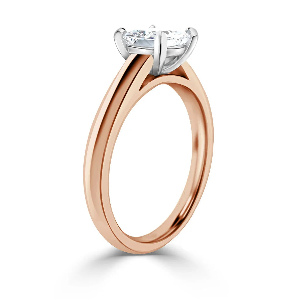 A rose gold engagement ring with a round solitaire diamond in a white gold prong setting, shown side view.