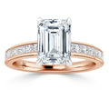 A rose gold ring with an emerald-cut diamond center and channel-set diamonds along the band.