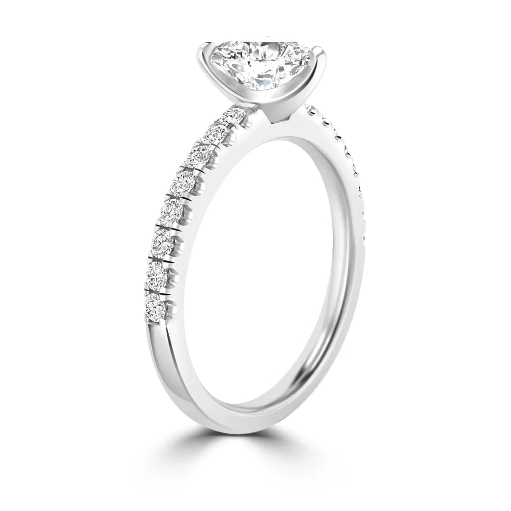 A white gold ring with a round solitaire diamond and small diamonds set along the band.