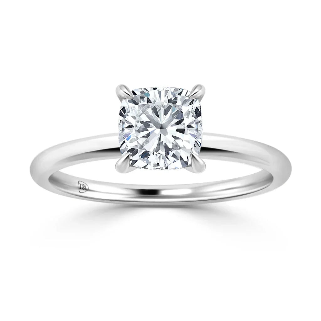 A silver solitaire ring with a cushion-cut diamond set in a four-prong setting on a plain band.