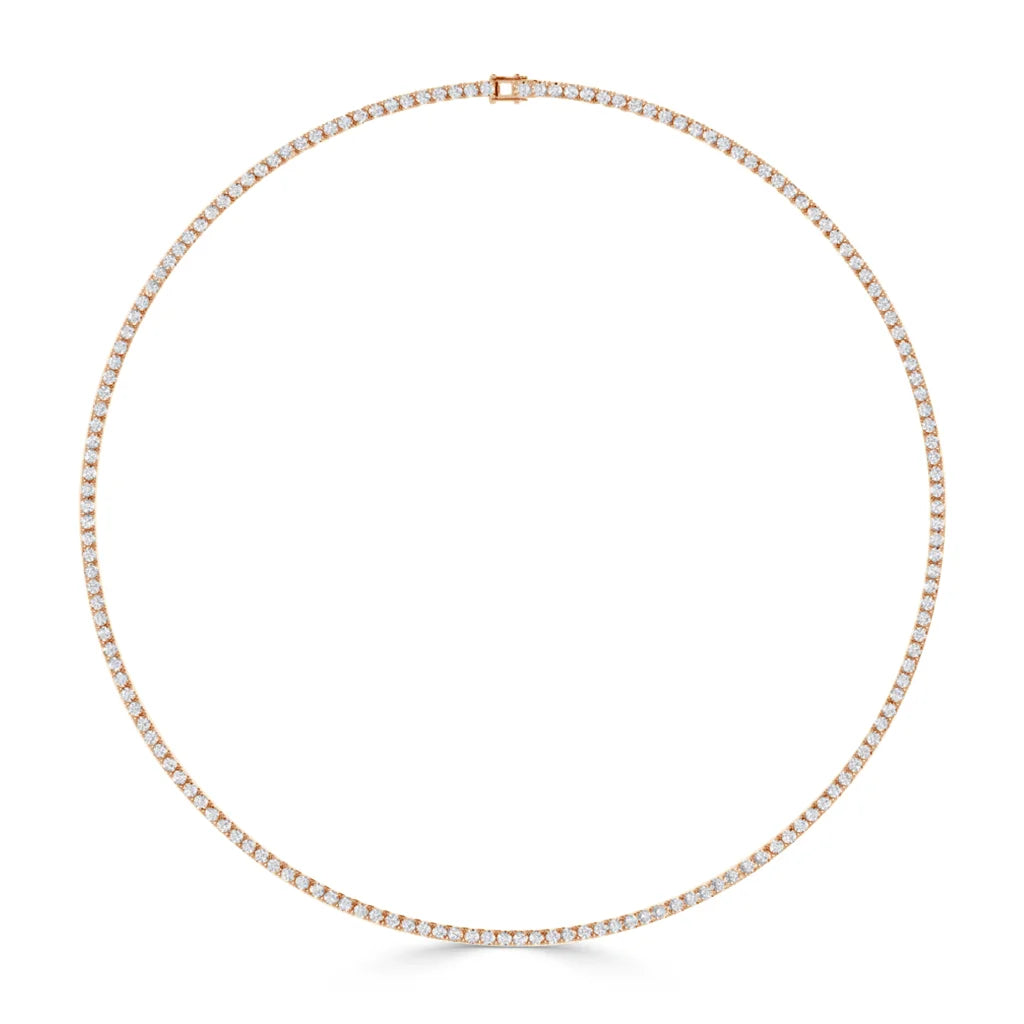 A thin gold tennis necklace with small, evenly spaced diamonds in a full circle on a white background.