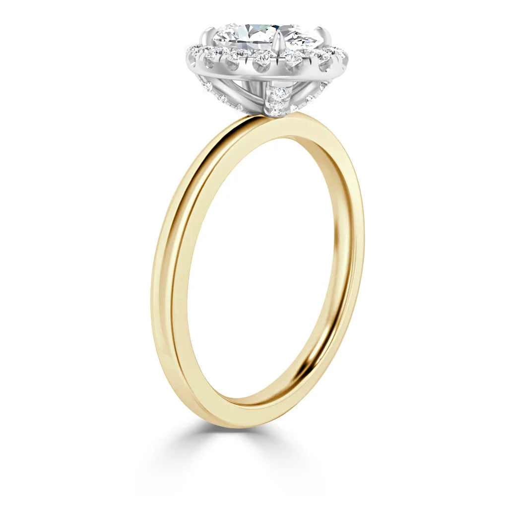 Gold ring with a round diamond halo setting in white metal, viewed from the side against a white background.