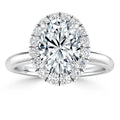 Oval diamond ring with a halo of smaller diamonds set on a shiny, polished white metal band.