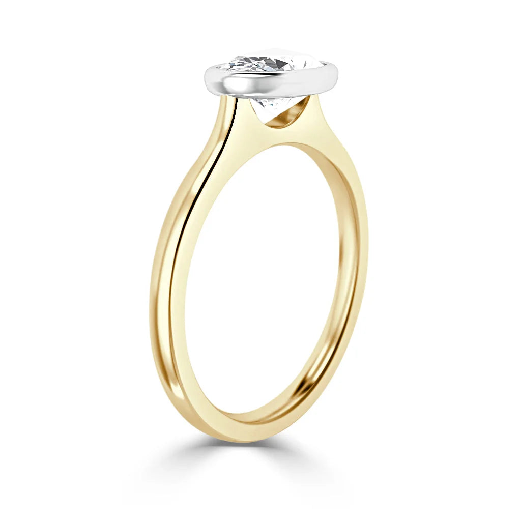 A gold ring with a round diamond set in a sleek, raised white bezel setting, shown on a white background.
