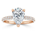 A pear-shaped diamond ring with a rose gold band, accented by small pavé diamonds along the band.