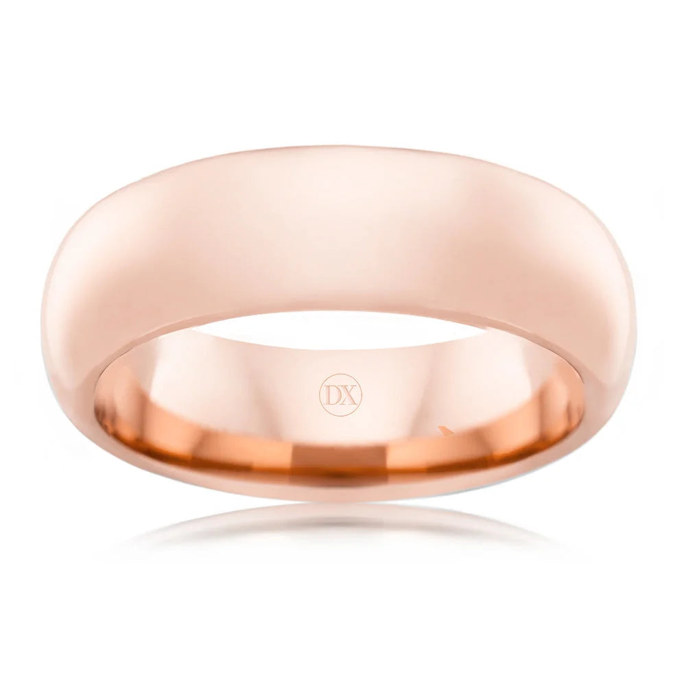 A polished rose gold wedding band with a smooth, rounded surface and a DX engraving inside.
