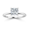 A cushion-cut diamond solitaire ring with a thin, polished white metal band on a white background.
