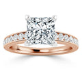 A rose gold ring with a large princess-cut diamond and smaller diamonds set along the band.