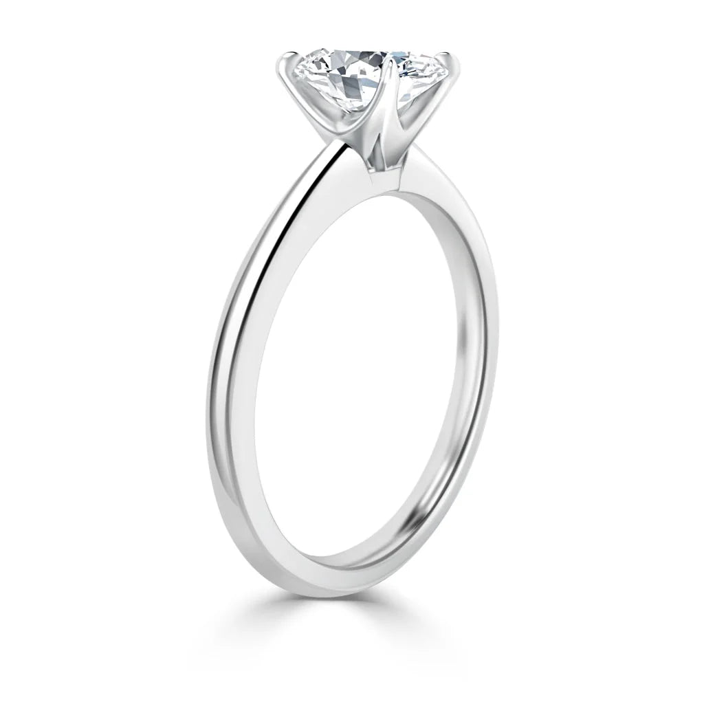 A silver solitaire engagement ring with a single round diamond in a prong setting, shown from the side.