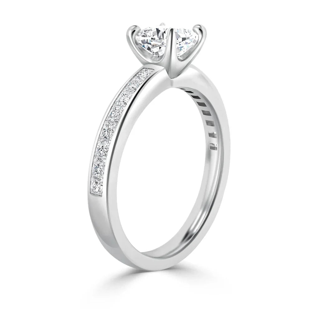 A white gold ring with a heart-shaped diamond and small diamonds set along the band’s upper half.