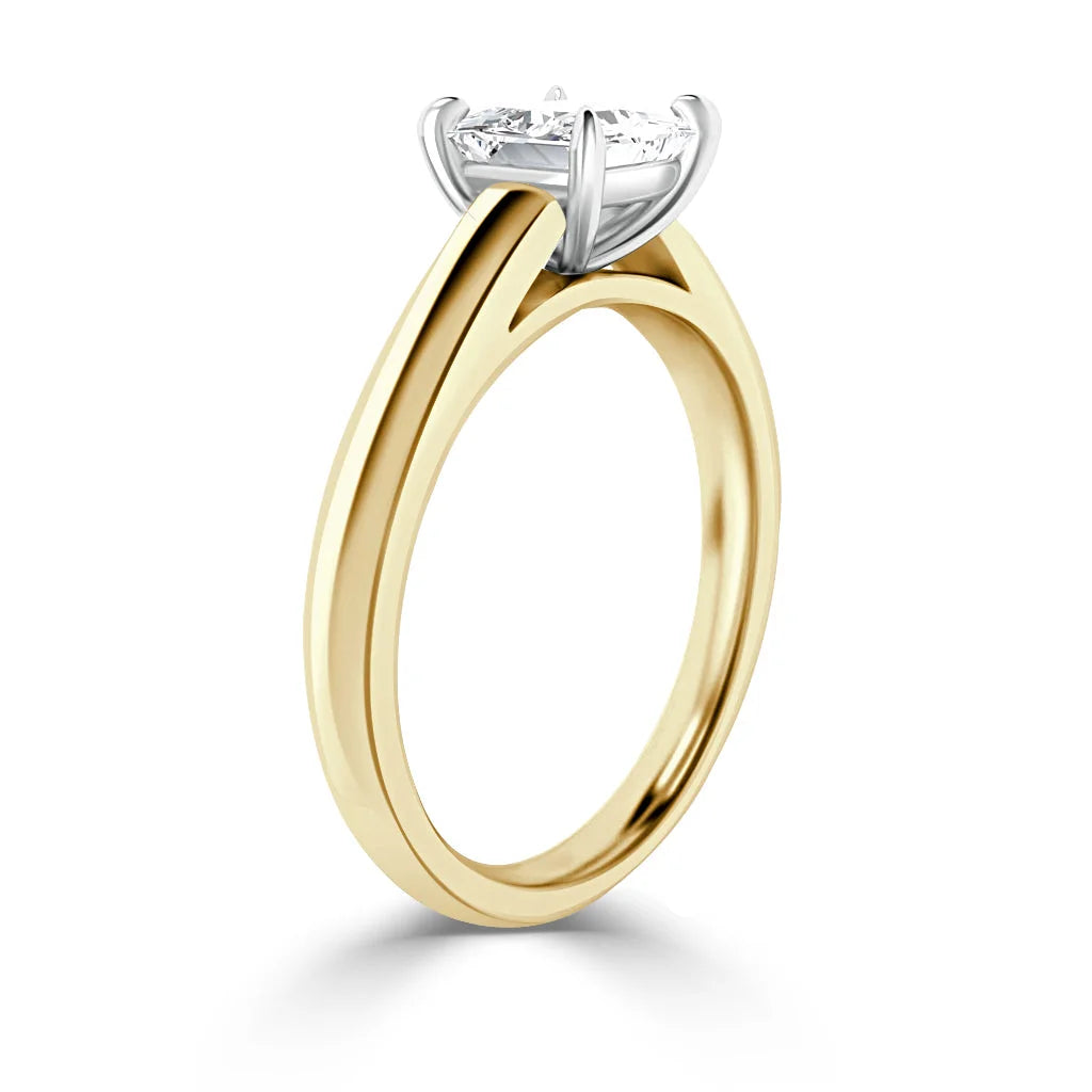 A gold ring with a solitaire round diamond set in a white gold four-prong setting, shown on a white background.