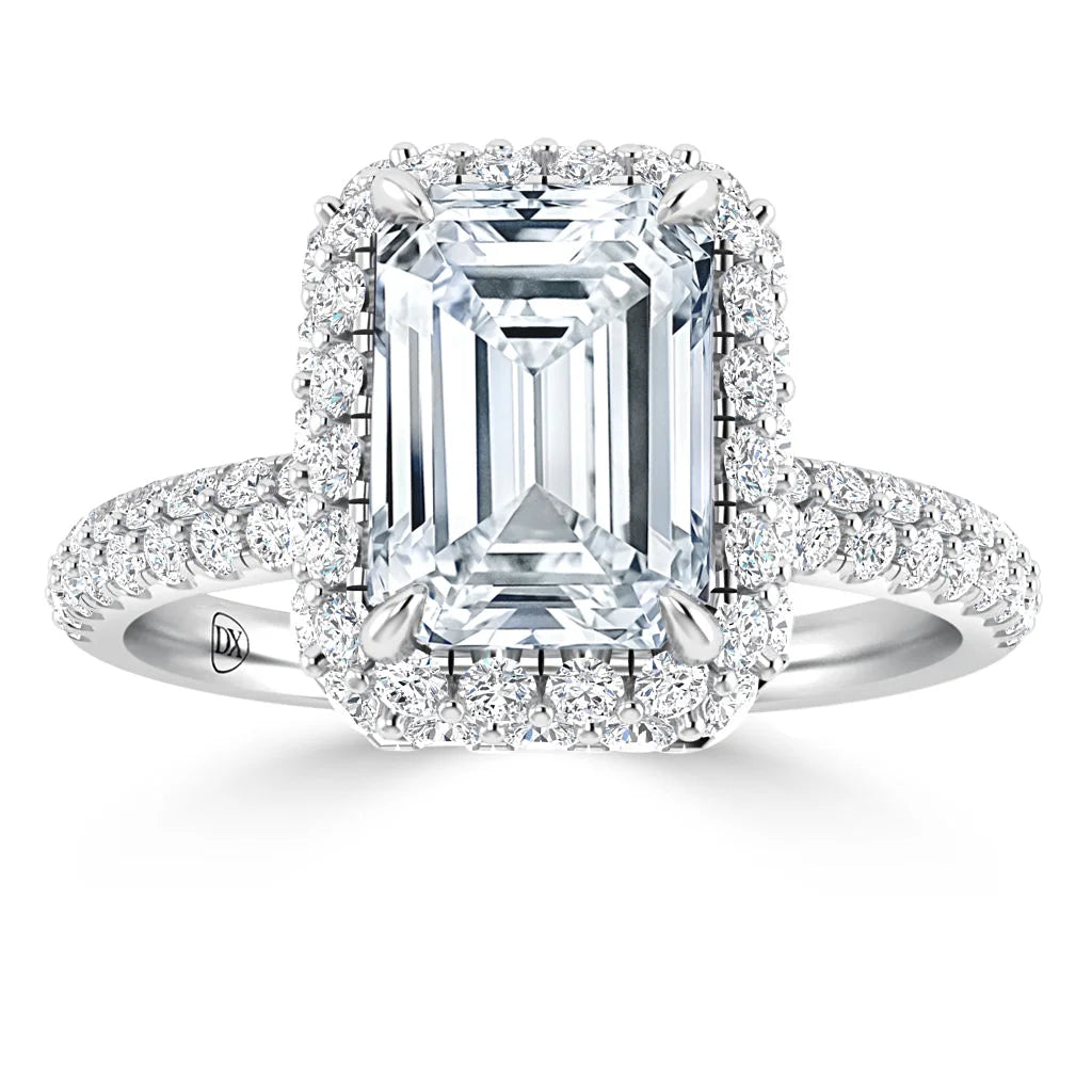 Emerald-cut diamond ring with a double halo of small round diamonds on a pavé diamond band.