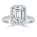 Emerald-cut diamond ring with a double halo of small round diamonds on a pavé diamond band.
