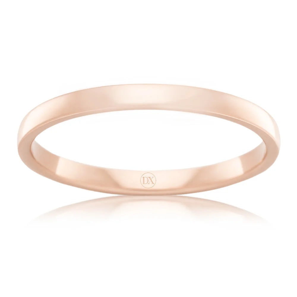A thin, polished rose gold ring with a simple, smooth design and a small DX engraving inside.