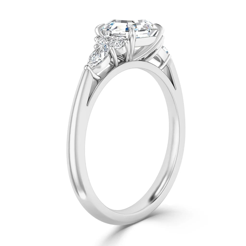 A white gold ring with a large round diamond and two smaller side diamonds in a prong setting.