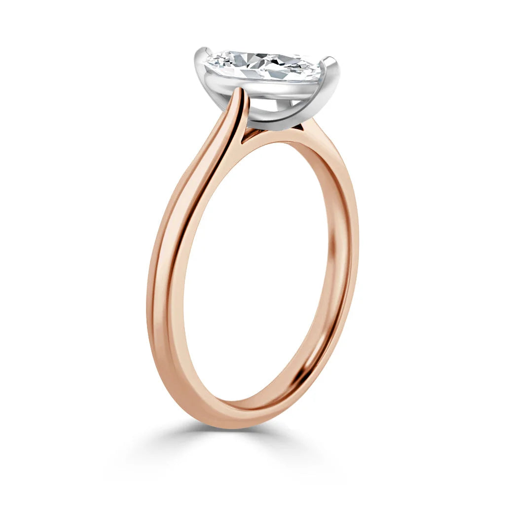 A rose gold solitaire ring with a round diamond set in a white gold prong setting, viewed from the side.