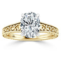 Gold ring with an oval diamond center and intricate filigree designs on the band, against a white background.