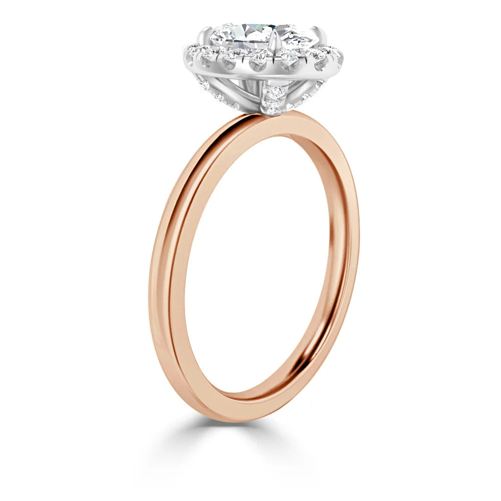 Rose gold ring with a round diamond solitaire in a white gold prong setting, viewed from the side.