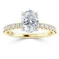 Gold ring with an oval diamond center stone and small round diamonds along the band, shown on a white background.